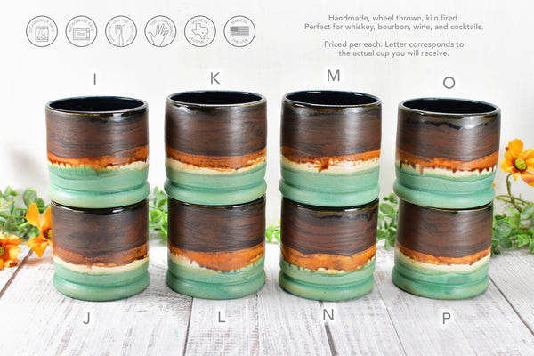 display of 8 handmade wheel thrown ceramic pottery whiskey tumbler cups in brown, bronze and turquoise patina green glaze by artist Camille Woodward